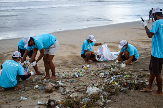 Litter along the shores of a beach being cleaned up