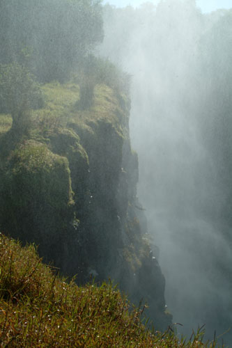 Thick spray of the Victoria Falls seen along a steep cliff in Zimbabwe