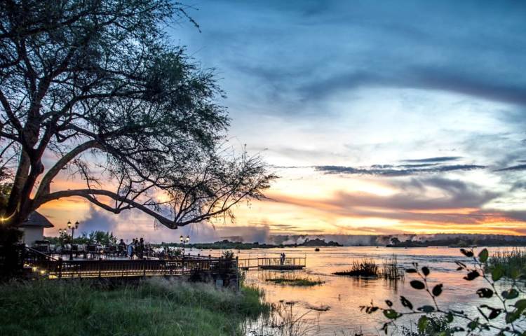The Royal Livingstone Hotel deck, the Zambezi River, the spray of the Victoria Falls, at sunset