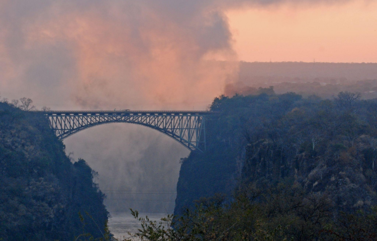 Sunrise over the Victoria Falls, with the Victoria Falls Bridge in the foreground